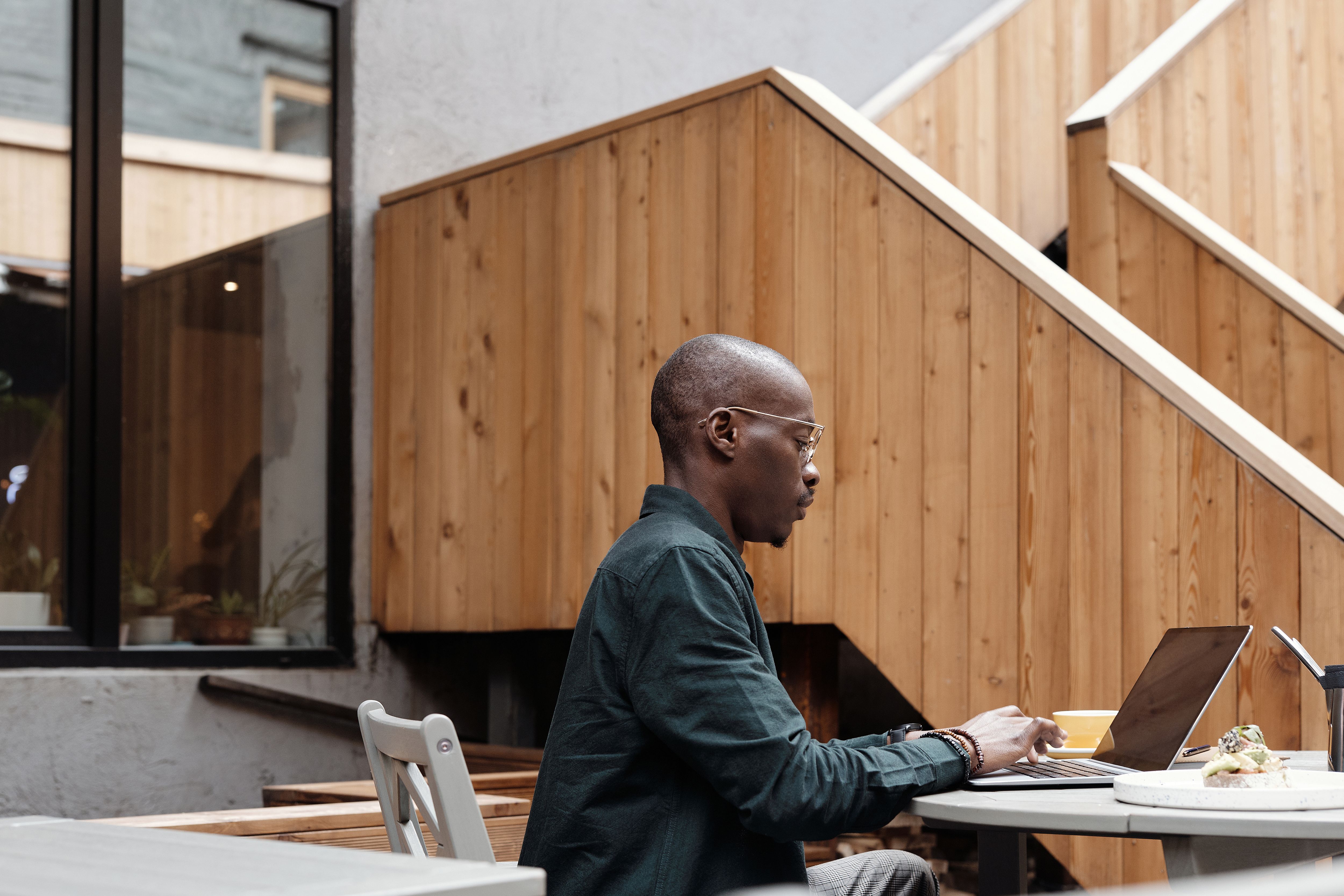 African American man working remotely on a laptop at an outdoor café