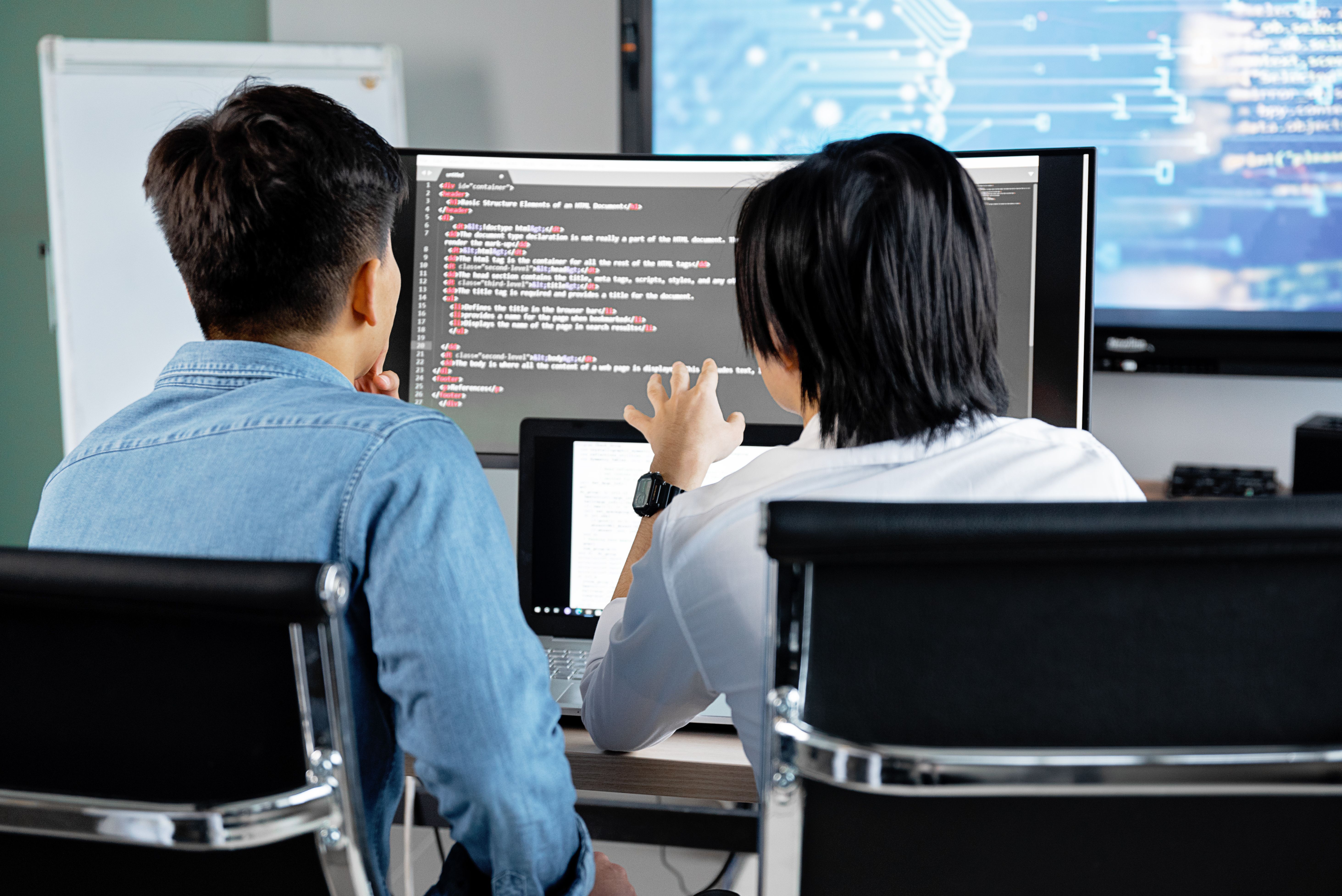 Two developers discussing work on a screen